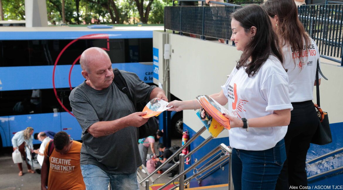 Foto de uma mulher distribuindo panfleto para um homem