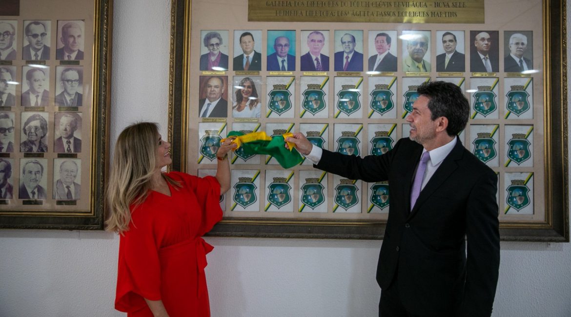 Mulher e homem retiram faixa que cobre fotografia na galeria de ex-diretores do Fórum de Fortaleza.