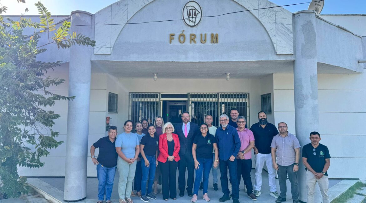 Foto com vários homens e mulheres na frente da fachada do Fórum