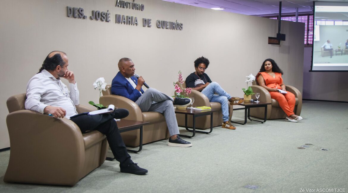 Imagem do palco com quatro pessoas sentadas durante uma palestra