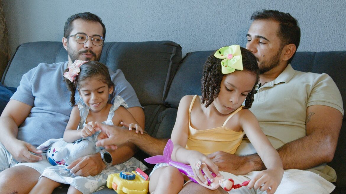 Foto com dois homens e duas crianças sentados em um sofá Foto com dois homens e duas crianças sentados em um sofá