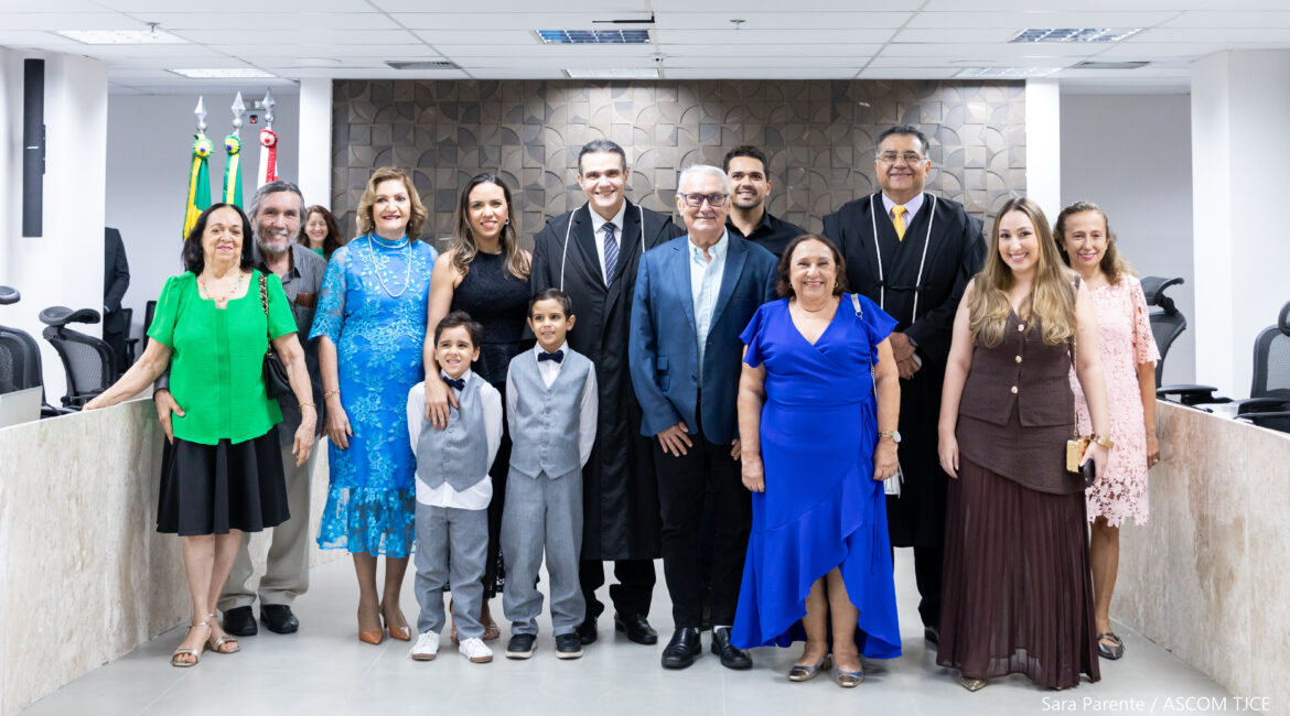 Homens, mulheres e crianças posam para a foto, sorrindo, no auditório