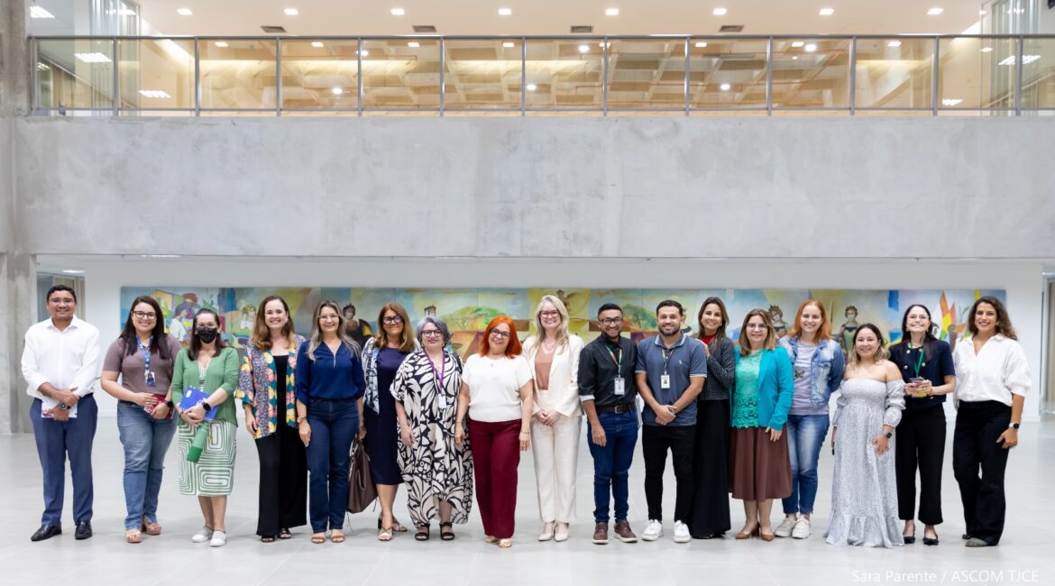Várias mulheres e homens, perfilhadas(os), sorrindo para foto, no hall do tribunal