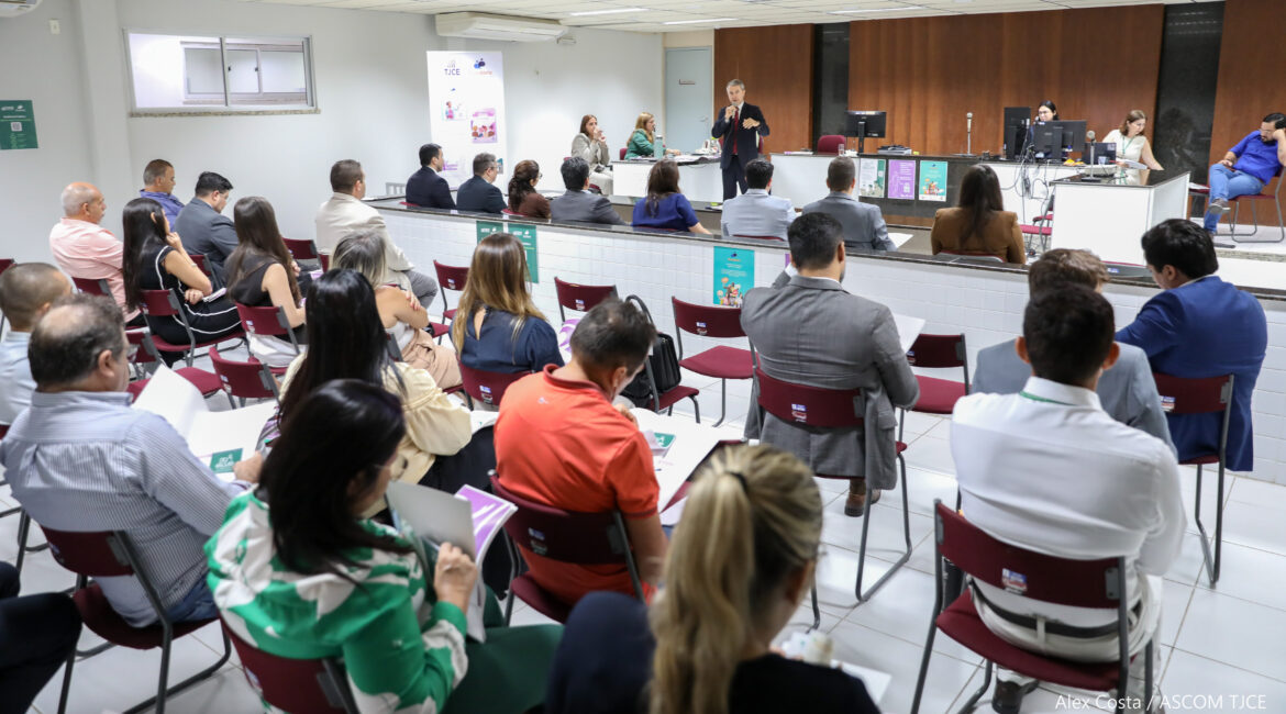 Foto de um homem com microfone na mão, falando para várias pessoas em um grande auditório Foto de um homem com microfone na mão, falando para várias pessoas em um grande auditório