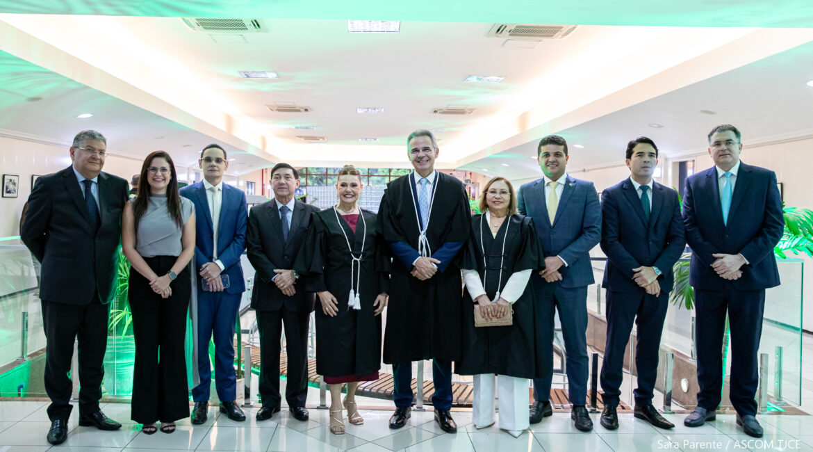Foto com homens e mulheres posando para foto, sorrindo, no hall da Esmec