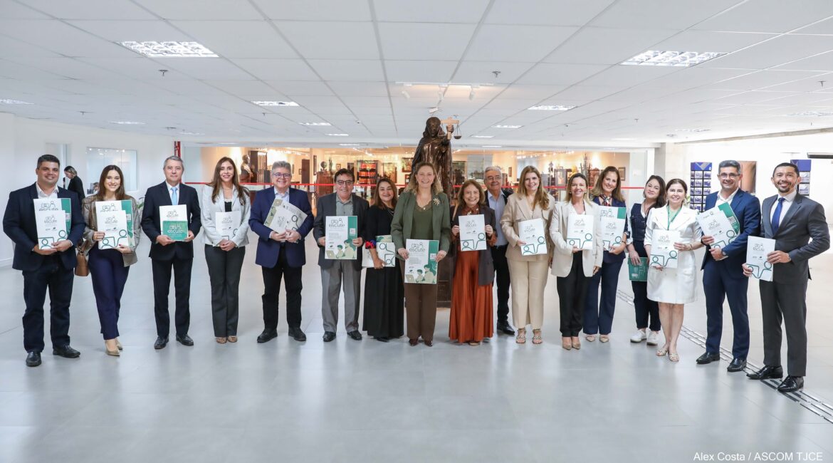 Foto de várias pessoas em pé, sorrindo, exibindo o panfleto da campanha