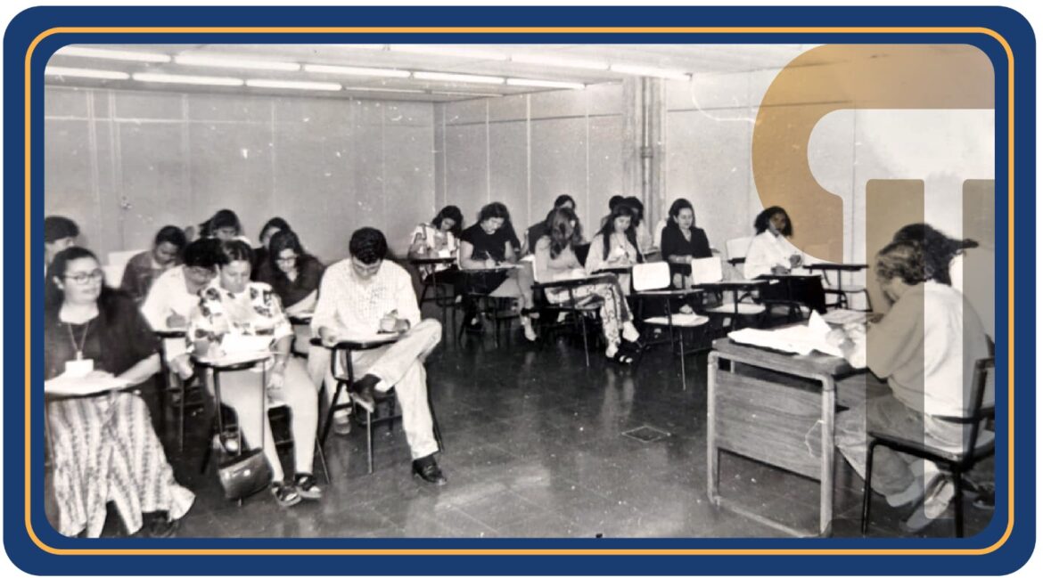 Foto antiga com várias pessoas sentadas em uma sala grande