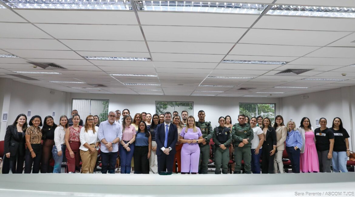 Imagem de várias mulheres e homens sorrindo, em pé, posando para foto