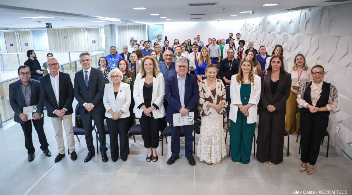 Imagem de várias mulheres e homens, sorrindo, posando para foto em um amplo espaço