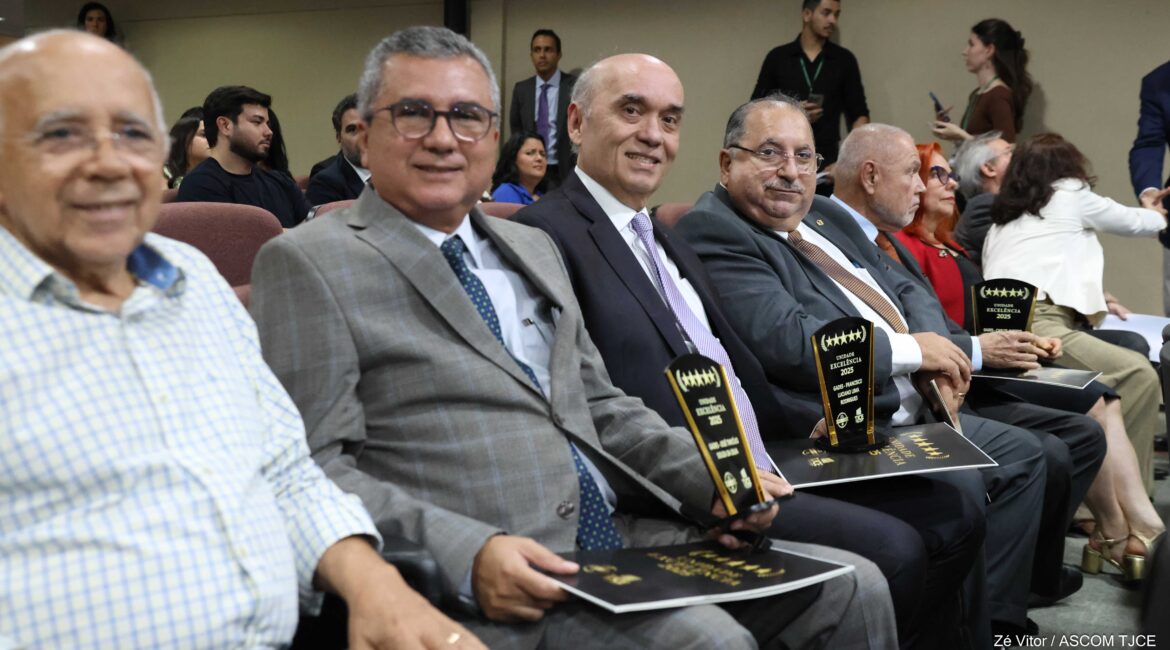 Foto de vários homens sorrindo, sentados, em um auditório