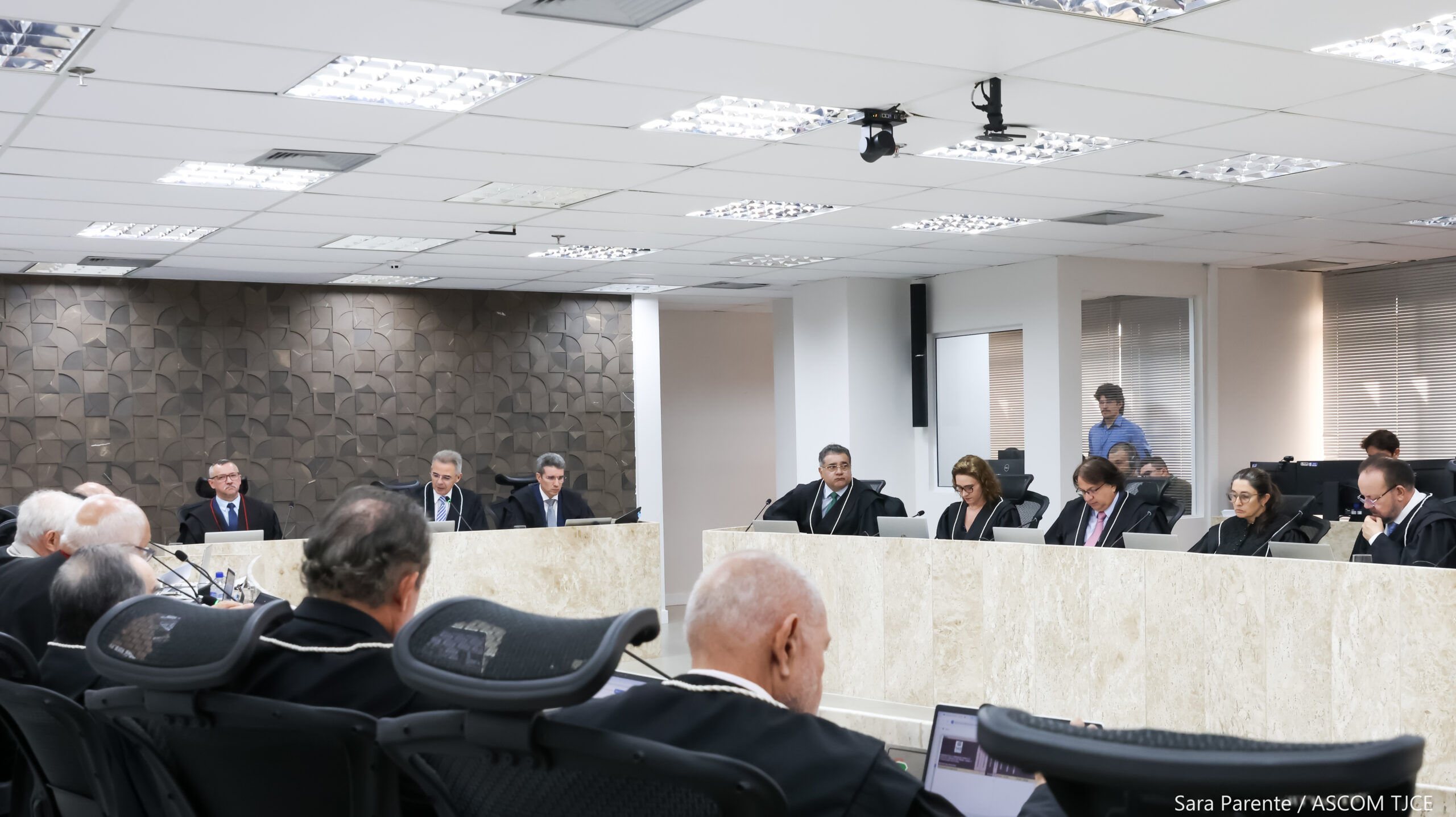 Várias pessoas sentadas ao redor de uma grande bancada de trabalho