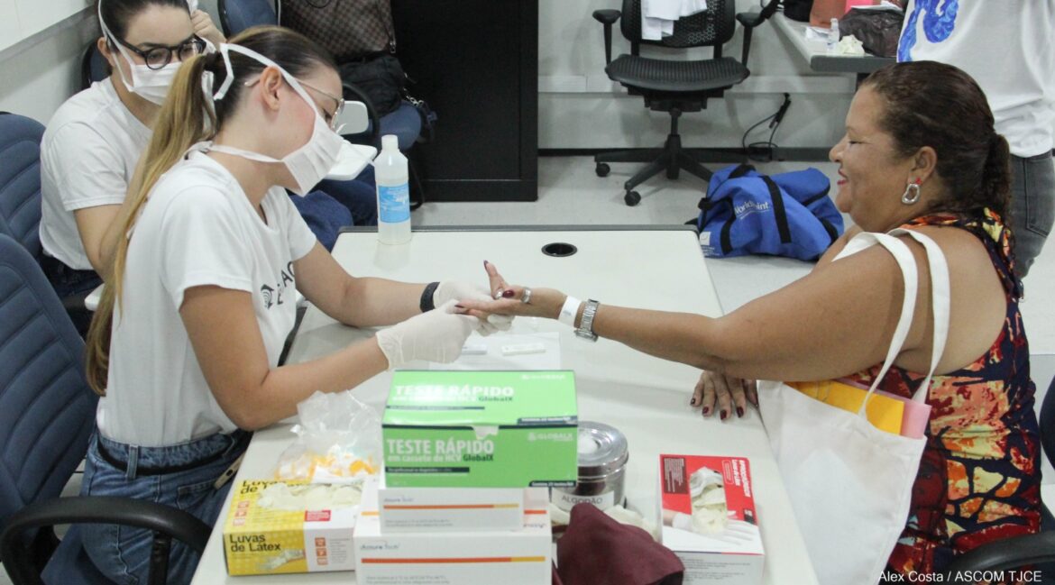 Foto de duas profissionais sentadas, fazendo atendimento de uma senhora também sentada