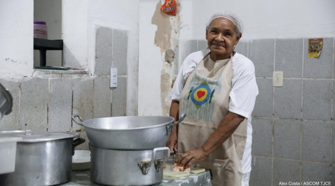 Foto de uma mulher cortando carne em uma cozinha