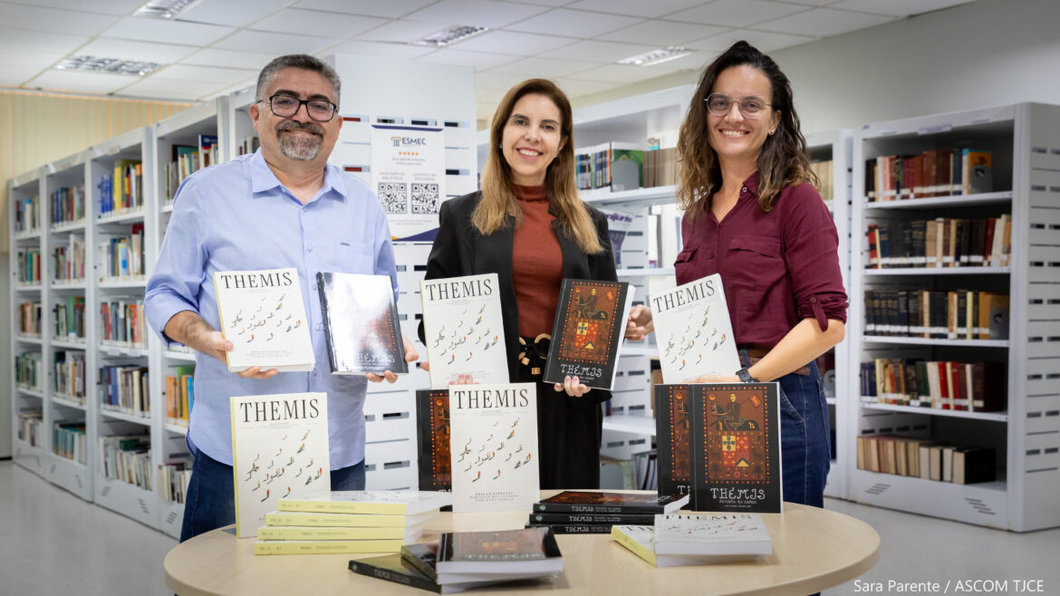 Foto de um homem e duas mulheres sorrindo, e exibindo exemplares de uma revista