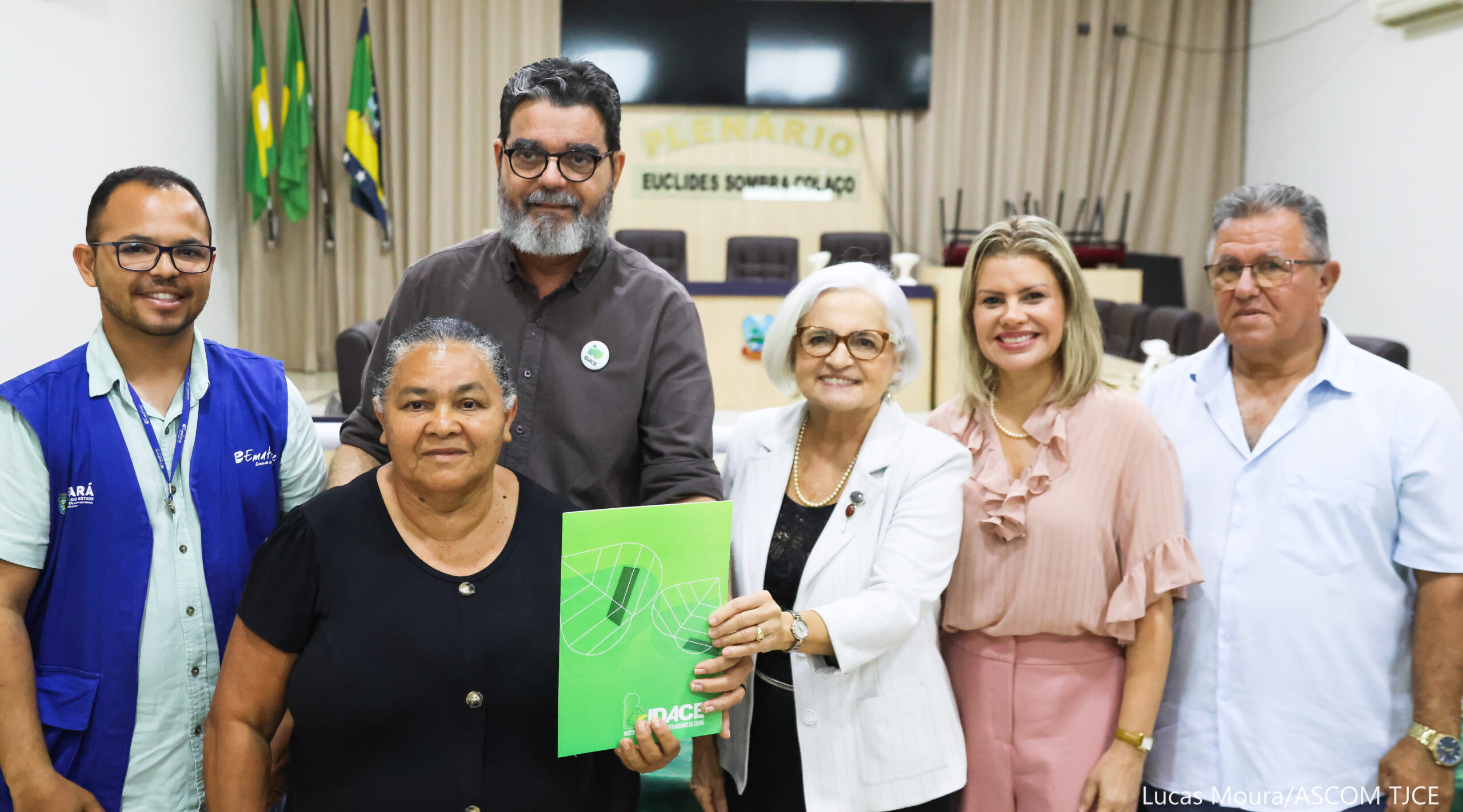 Cinco profissionais envolvidos posam de frente com uma moradora beneficiada.