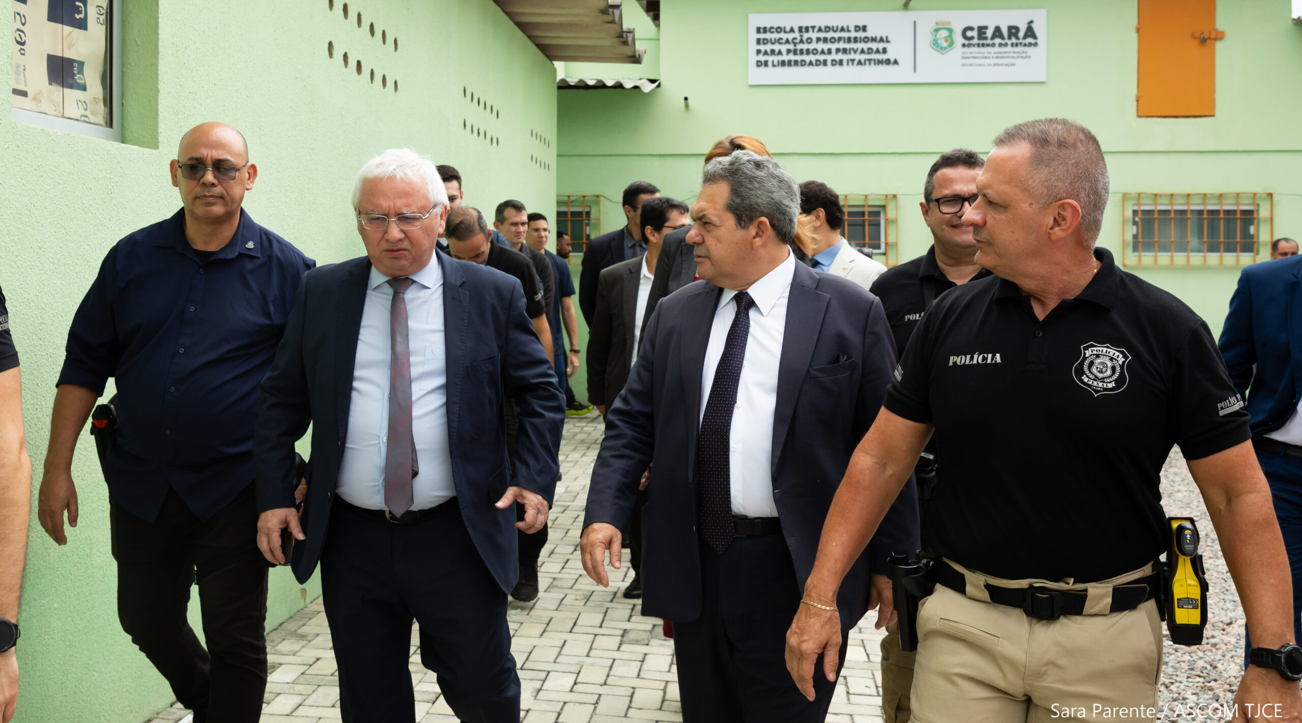 Foto de vários homens caminhando e conversando no pátio de uma prisão.