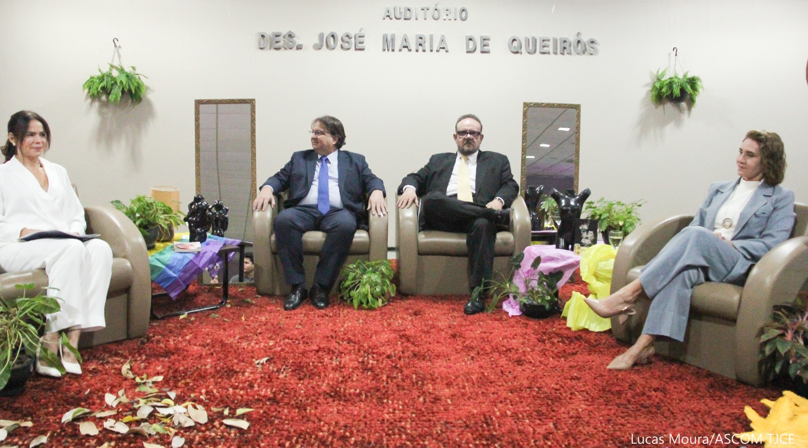 Fotografia de dois homens e duas mulheres sentados em poltronas, no palco de um auditório.