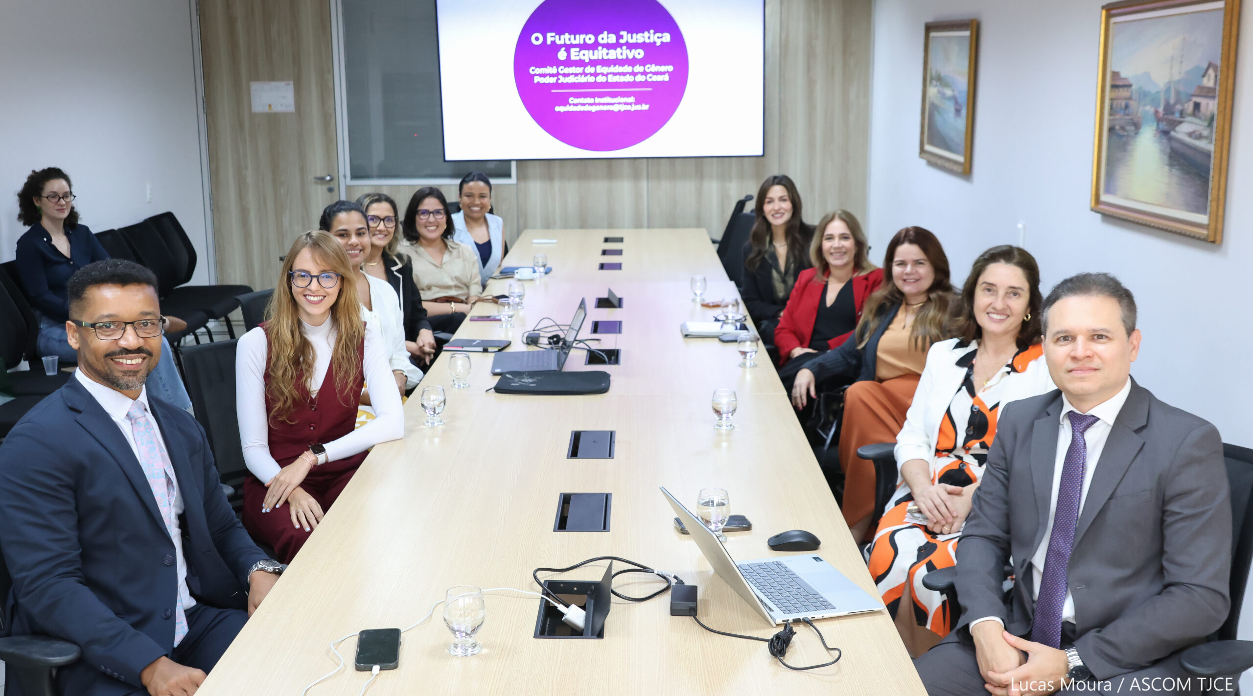 Foto de várias pessoas sentadas ao redor de uma mesa de trabalho, dialogando