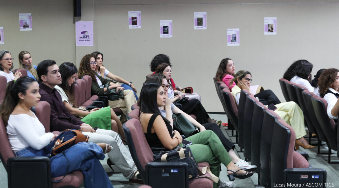 Foto com pessoas sentadas, na plateia de um auditório, ouvindo a palestrante Foto com pessoas sentadas, na plateia de um auditório, ouvindo a palestrante