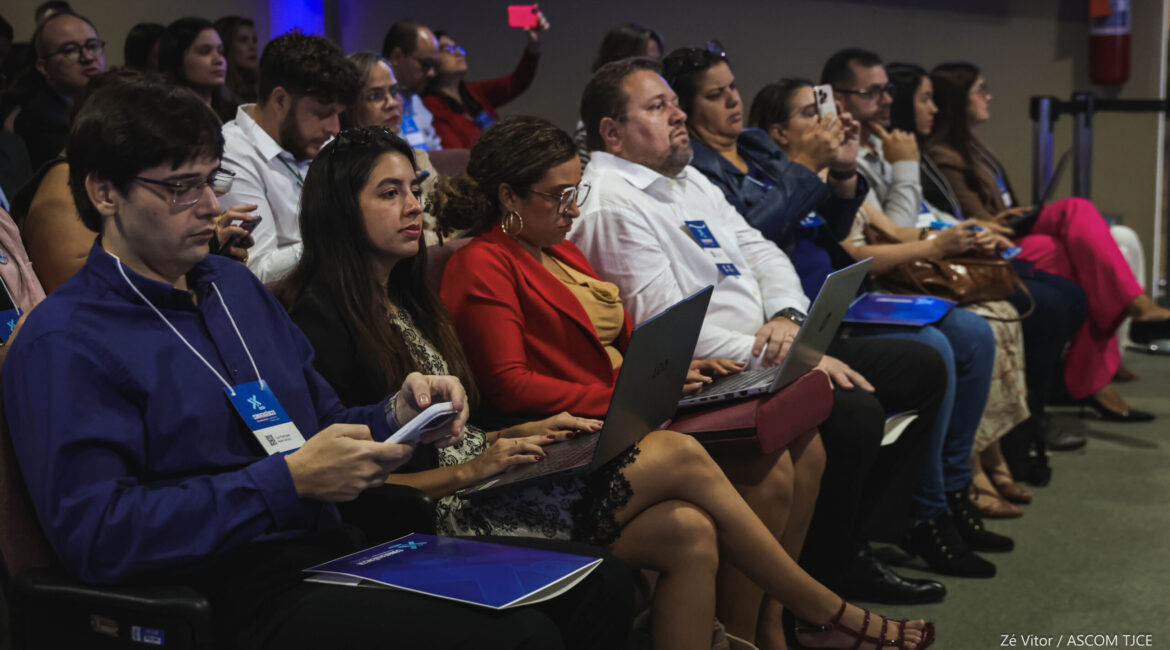Foto de vários homens e mulheres sentadas na plateia ouvindo a palestra
