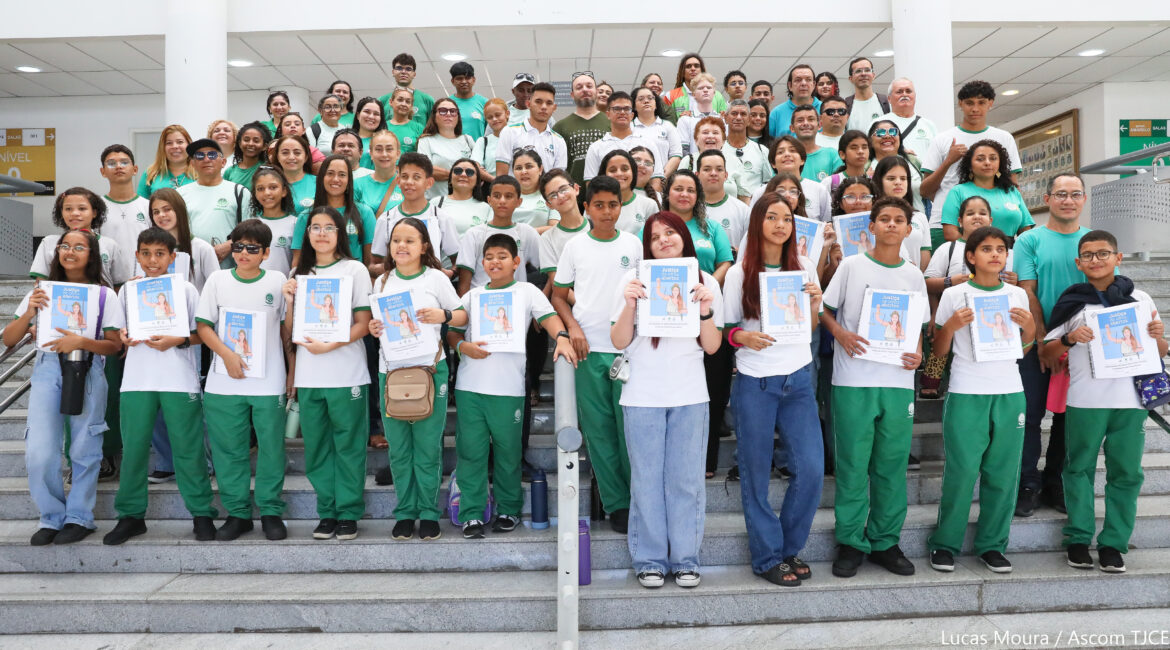 Imagem de várias crianças e adultos, posando para foto sorrindo, em pé, na escadaria do Fórum, segurando a cartilha Justiça de Olhos Abertos