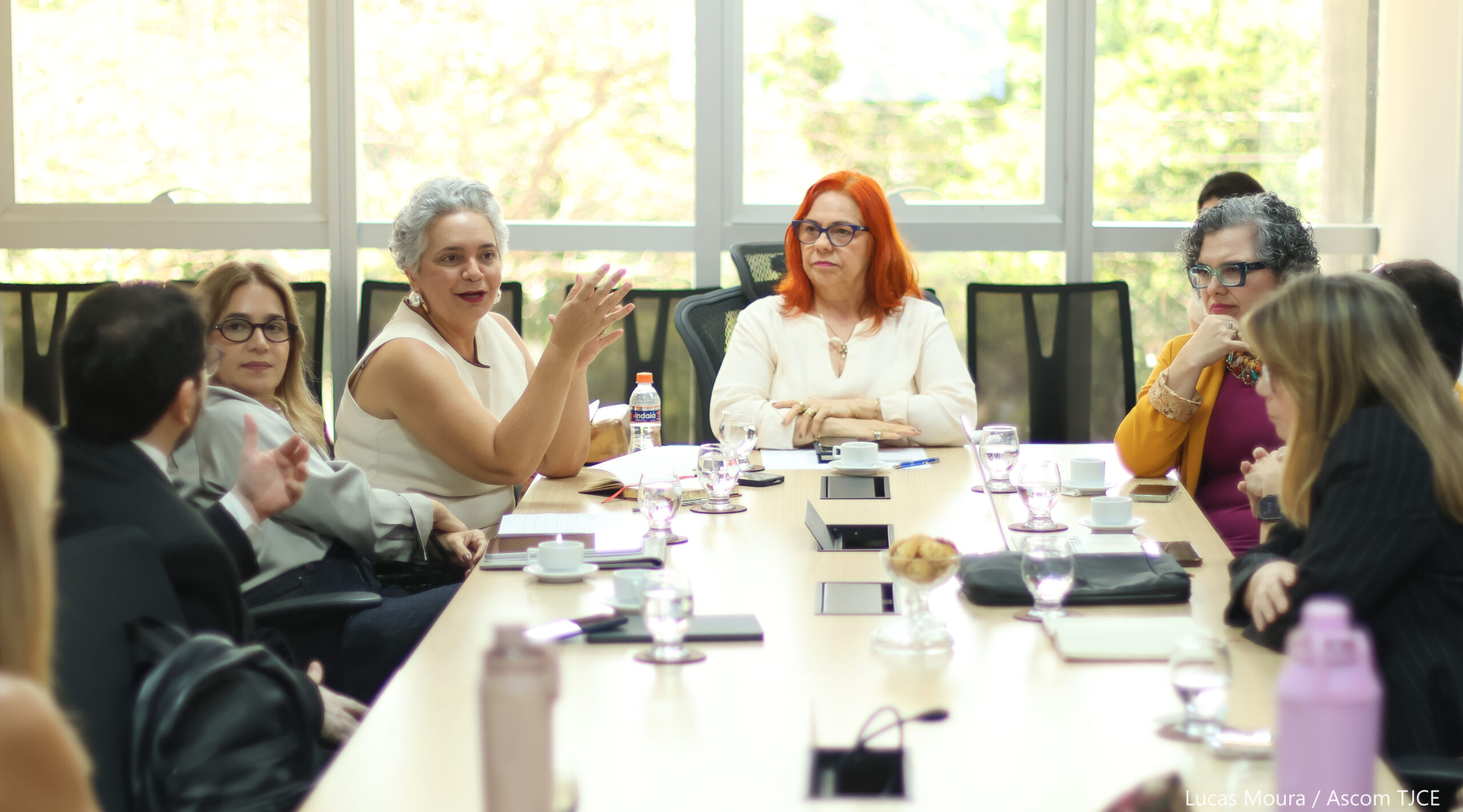 Várias pessoas sentadas em uma mesa de trabalho, dialogando