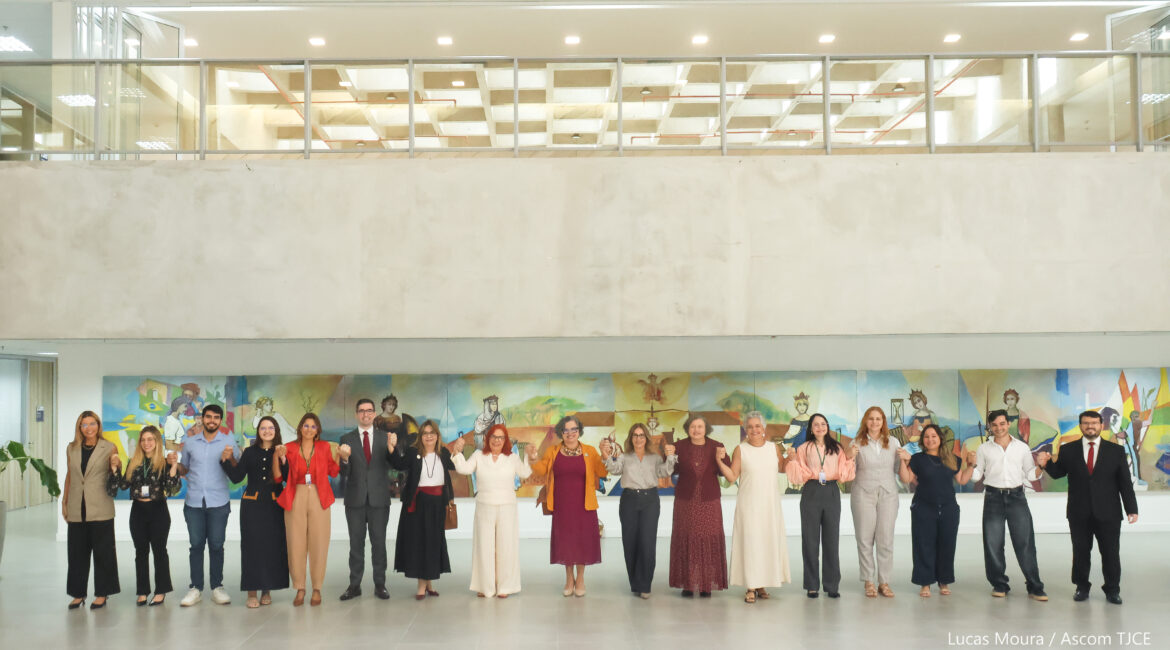 Vários homens e mulheres perfilhados, sorrindo, posando para foto no hall do Tribunal