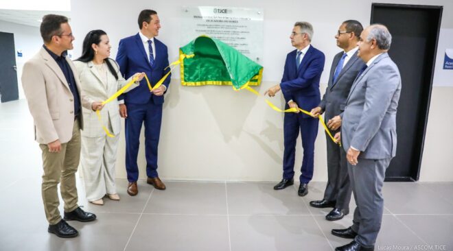 Seis pessoas formalmente vestidas removem pano que cobre a placa de reinauguração do prédio