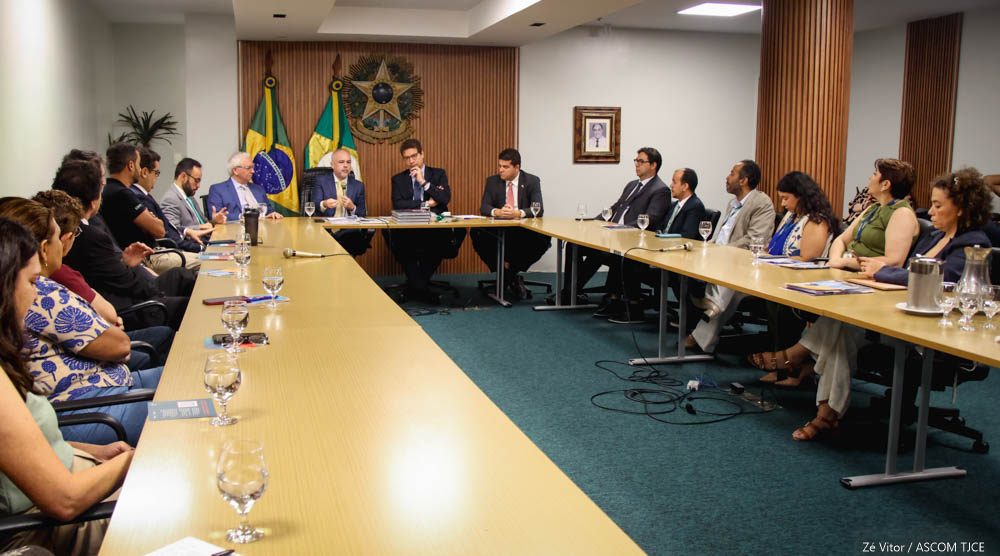 CNJ-3-1784838384-1784838384 Muitas pessoas sentadas ao redor de uma grande mesa de reuniões