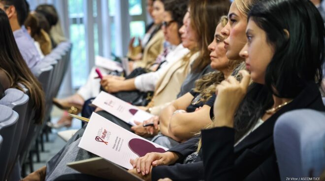 Mulheres na platéia escutam atentamente à apresentação