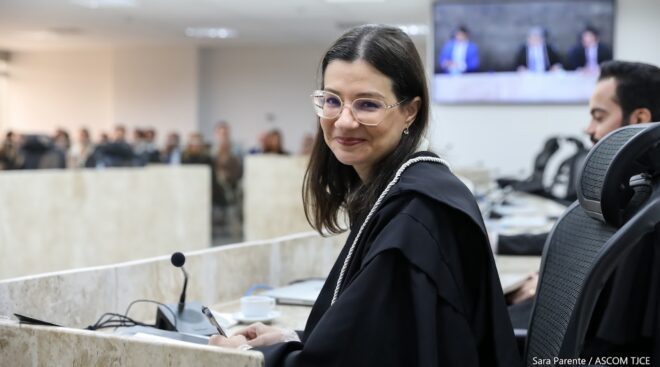 A imagem mostra a juíza que tomou posse sentada e sorrindo