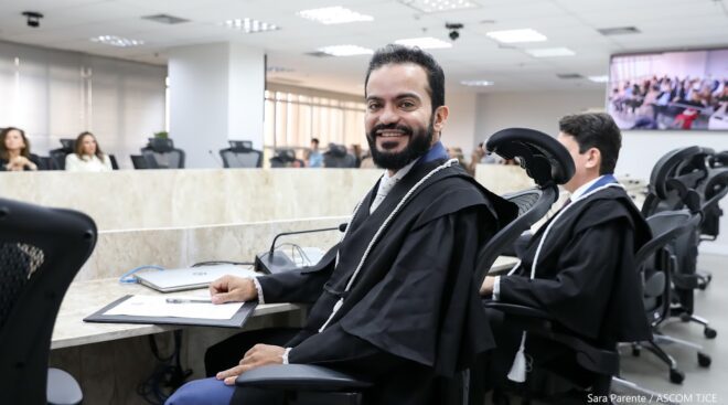 A imagem mostra um dos juízes que tomou posse sentado e sorrindo