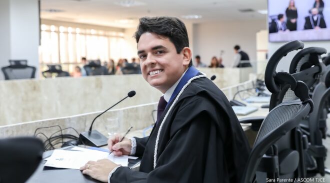 A imagem mostra um dos juízes que tomou posse sentado e sorrindo