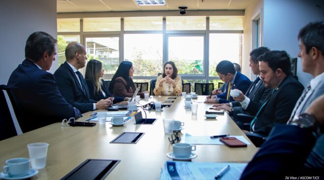 Grupo de pessoas conversam ao redor de uma grande mesa