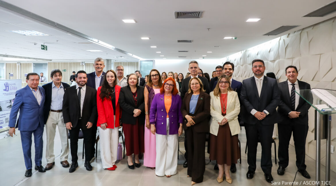 Grupo de mulheres e homens sorrindo para foto, em pé, ao final do evento