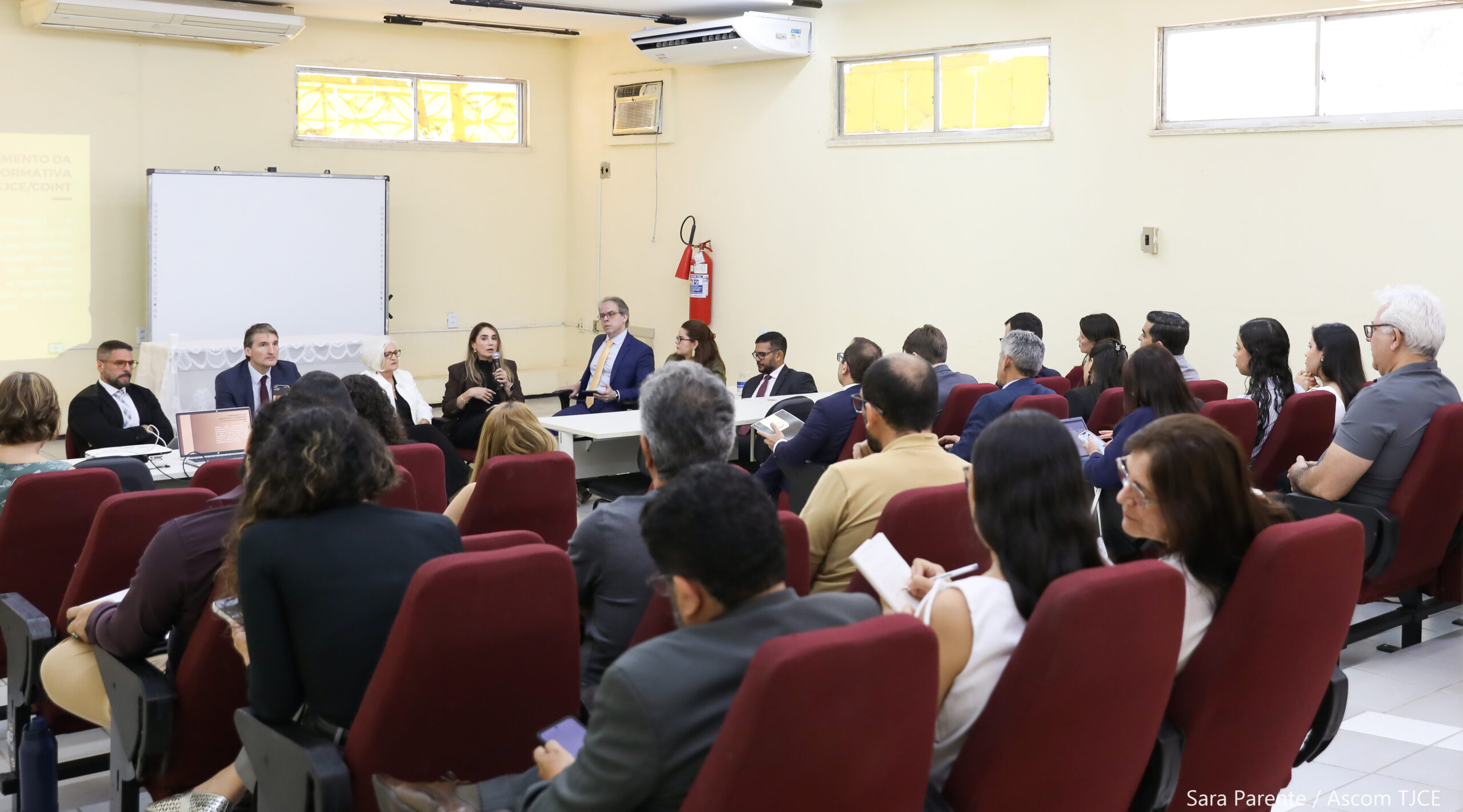 Foto de um auditório em que se encontram várias pessoas sentadas, e à frente delas, uma equipe de profissionais da Corregedoria dando as explicações