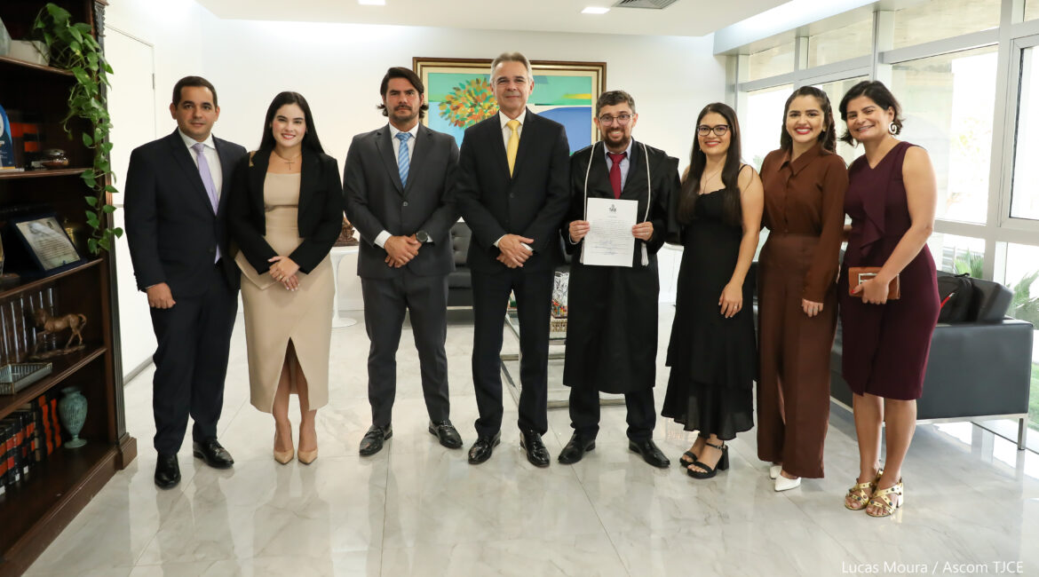 Imagem de quatro mulheres e quatro homens, todos em pé, sorrindo para foto, em uma sala de cor branca