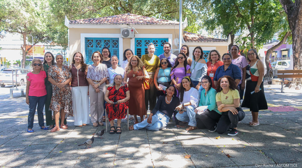 Imagem de várias mulheres e um homem, agachadas e em pé, sorrindo para foto