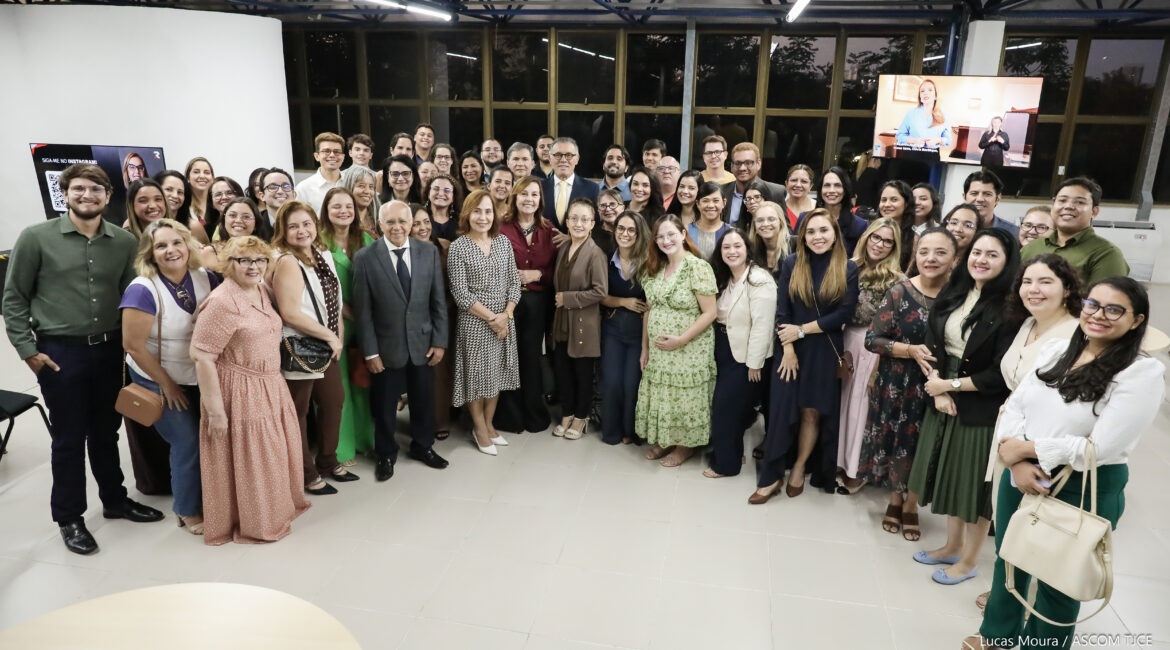 Várias pessoas em pé, posando para foto, sorrindo, em um amplo espaço