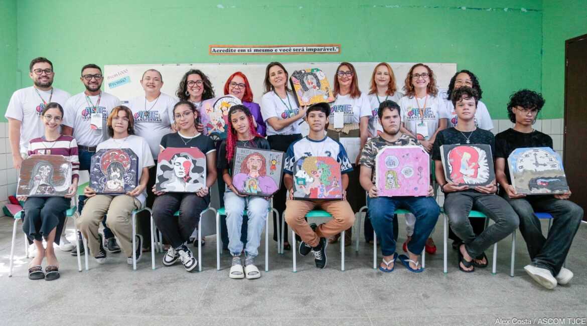 Várias mulheres, homens e jovens estudantes exibindo quadros de artes por eles produzidos
