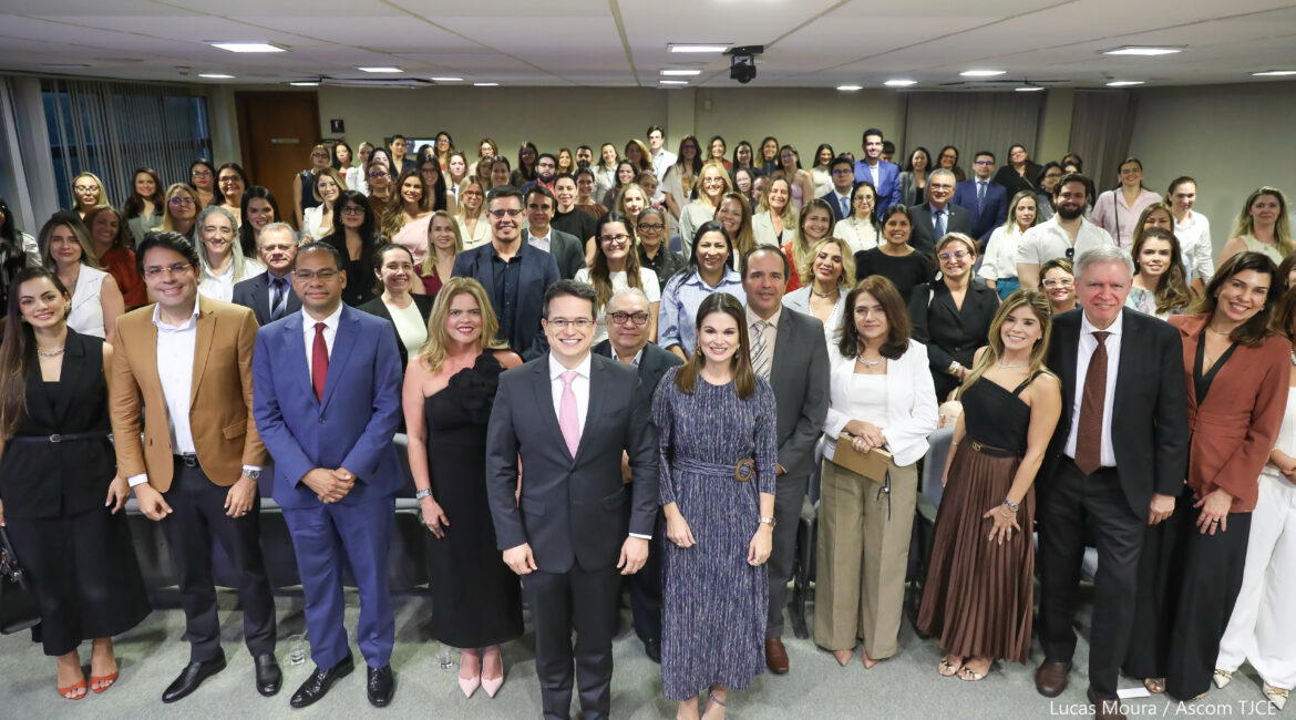 Imagem de vários homens e mulheres posando para foto, em pé, sorrindo