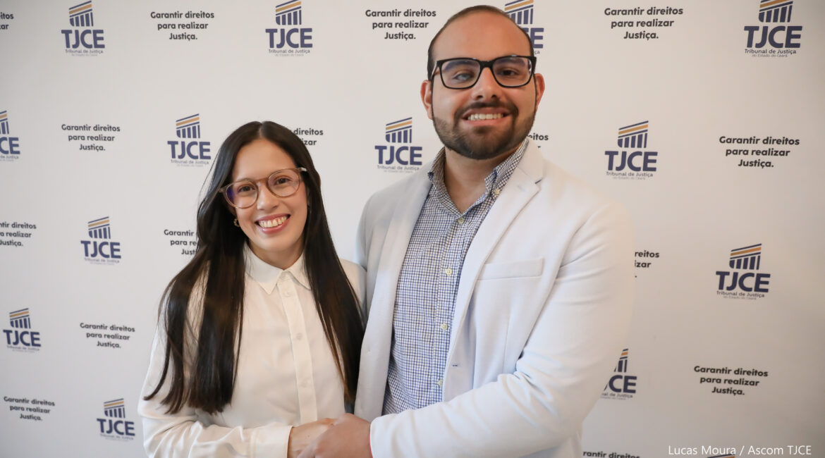 Imagem de um casal abraçado, homem e mulher, sorrindo para foto, em pé,