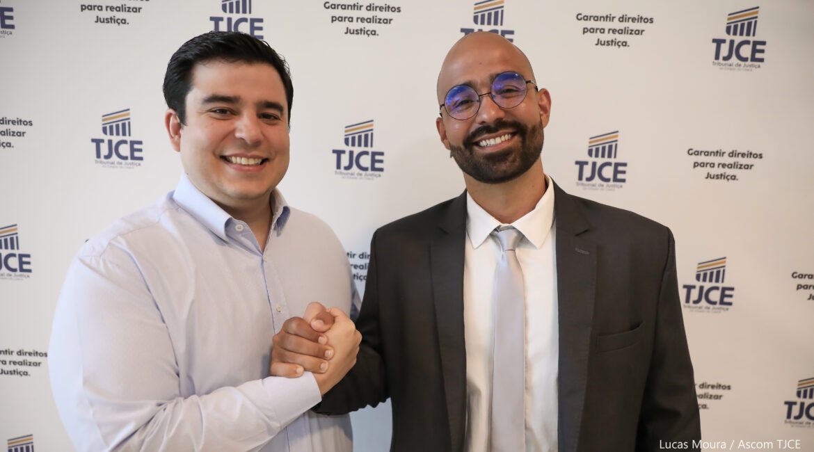 Imagem de dois irmãos, se cumprimentando, em pé, sorrindo para foto
