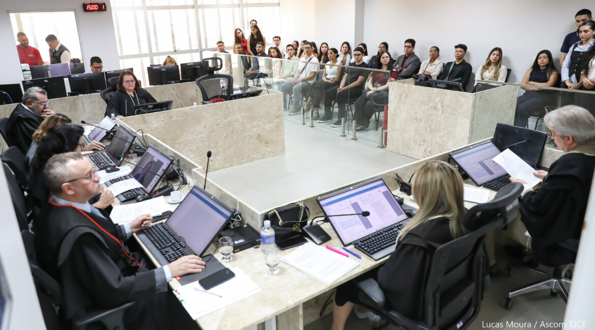 Sala de Julgamentos, onde estão os desembargadores e desembargadoras sentadas na bancada, analisando os processos. Na parte externa da bancada, os estudantes acompanham sentados e sentadas as decisões