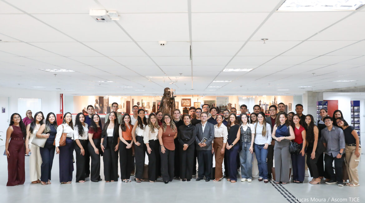Várias mulheres e homens posando para foto, em pé, sorrindo, no hall de entrada do TJCE