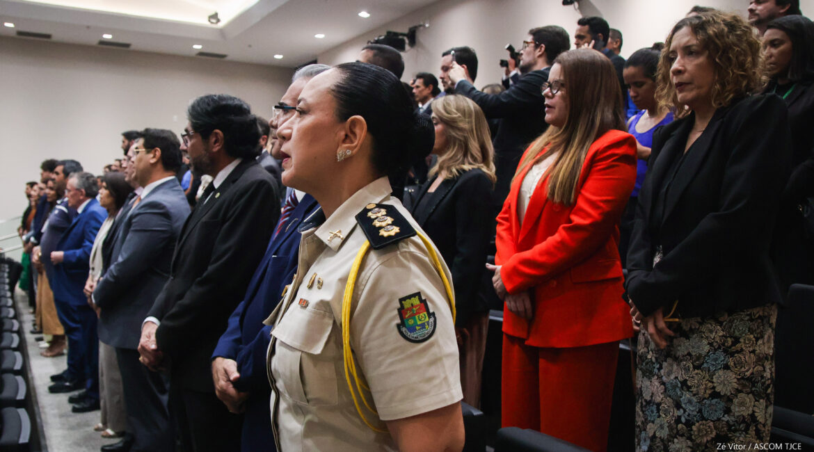 Foto de várias pessoas em pé, no auditório
