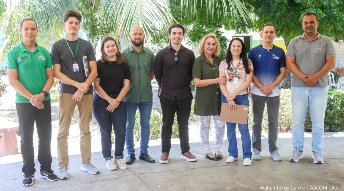 Mulheres e homens posando para foto, em pé, no jardim do estabelecimento
