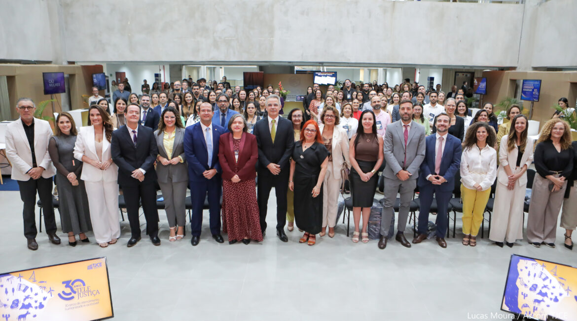 Imagem que mostra dezenas de homens e mulheres posando para foto, em pé, sorrindo, em um grande salão