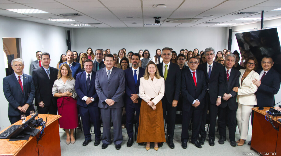 Vários homens e mulheres posando para foto, sorrindo, em pé, em um salão