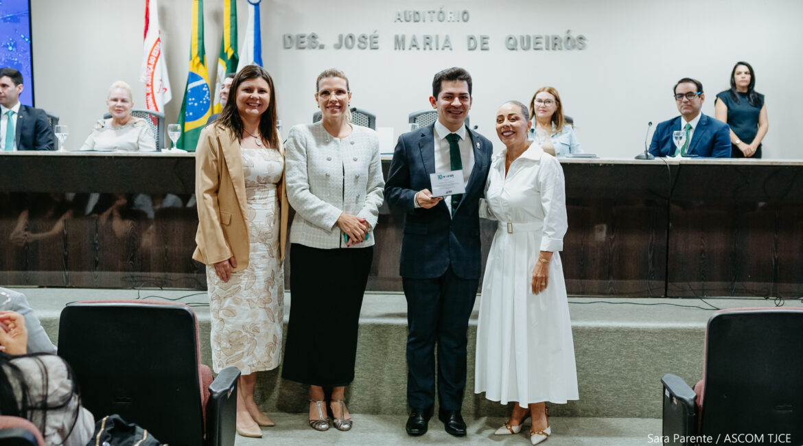 Foto de três mulheres e um homem sorrindo para foto, em pé